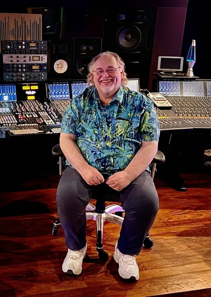 Michael D Clute in the control room in front of a large mixing console